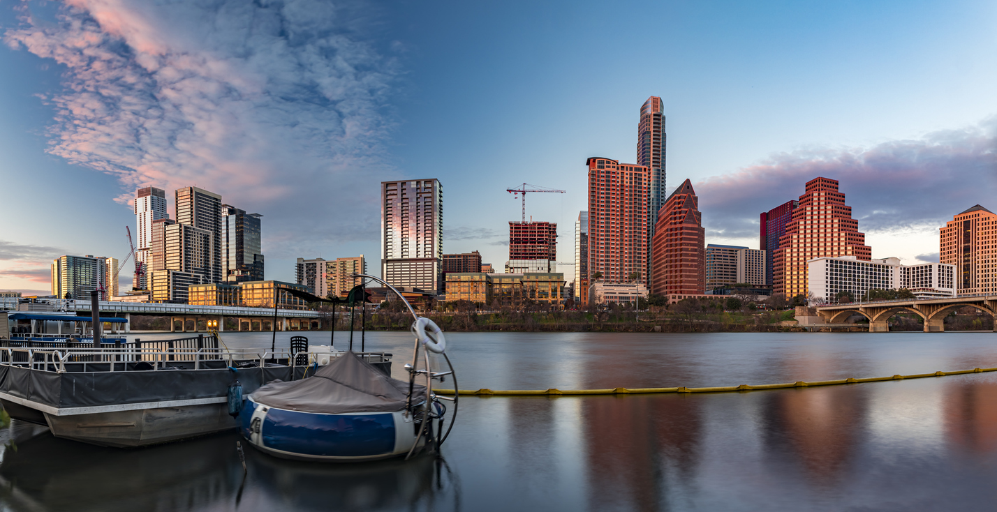 Panorama with downtown high-rises reflecting sunset golden hour light viewed across Lady Bird Lake