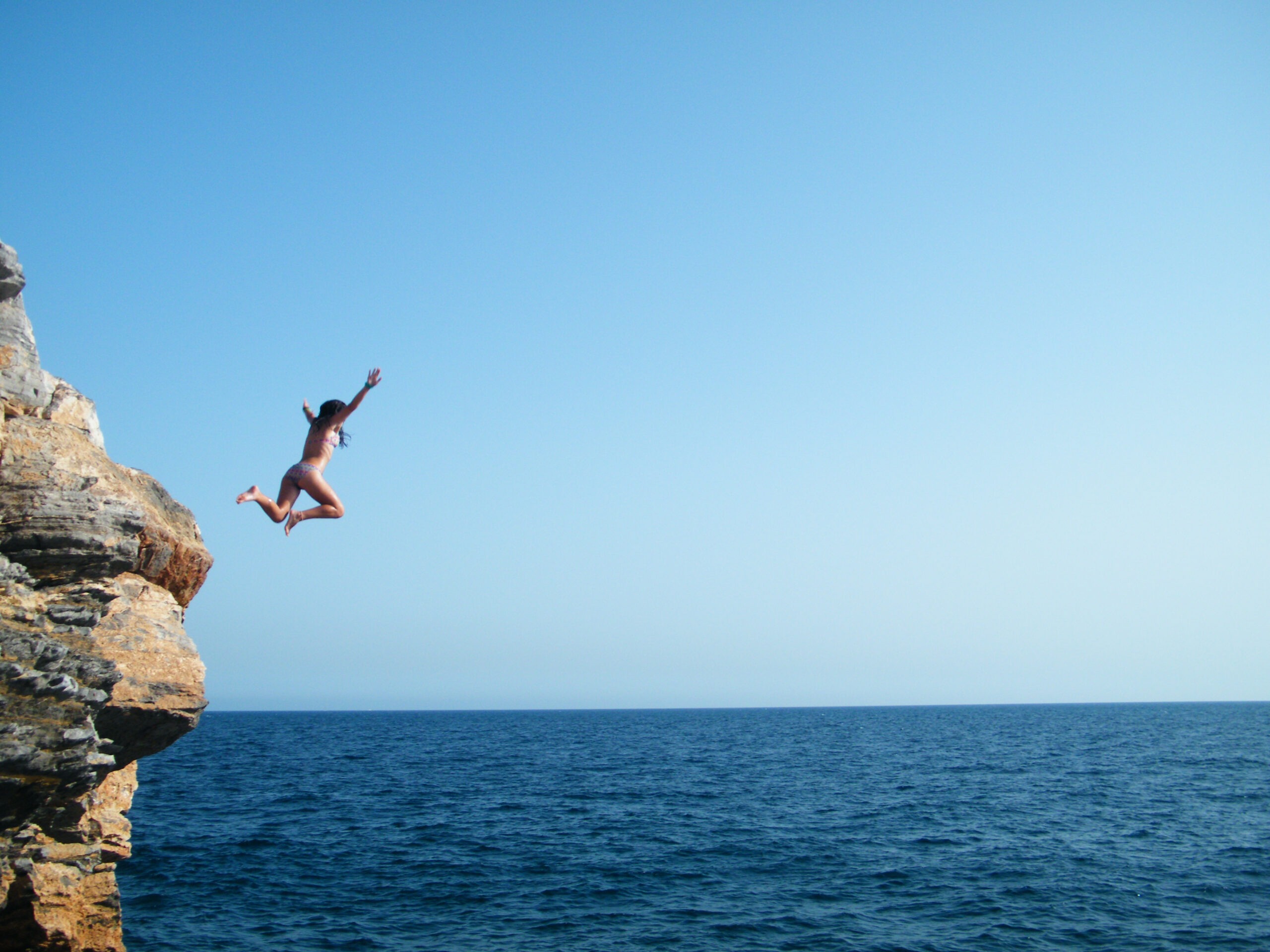 a-young-person-jumping-into-the-sea-from-the-rocks