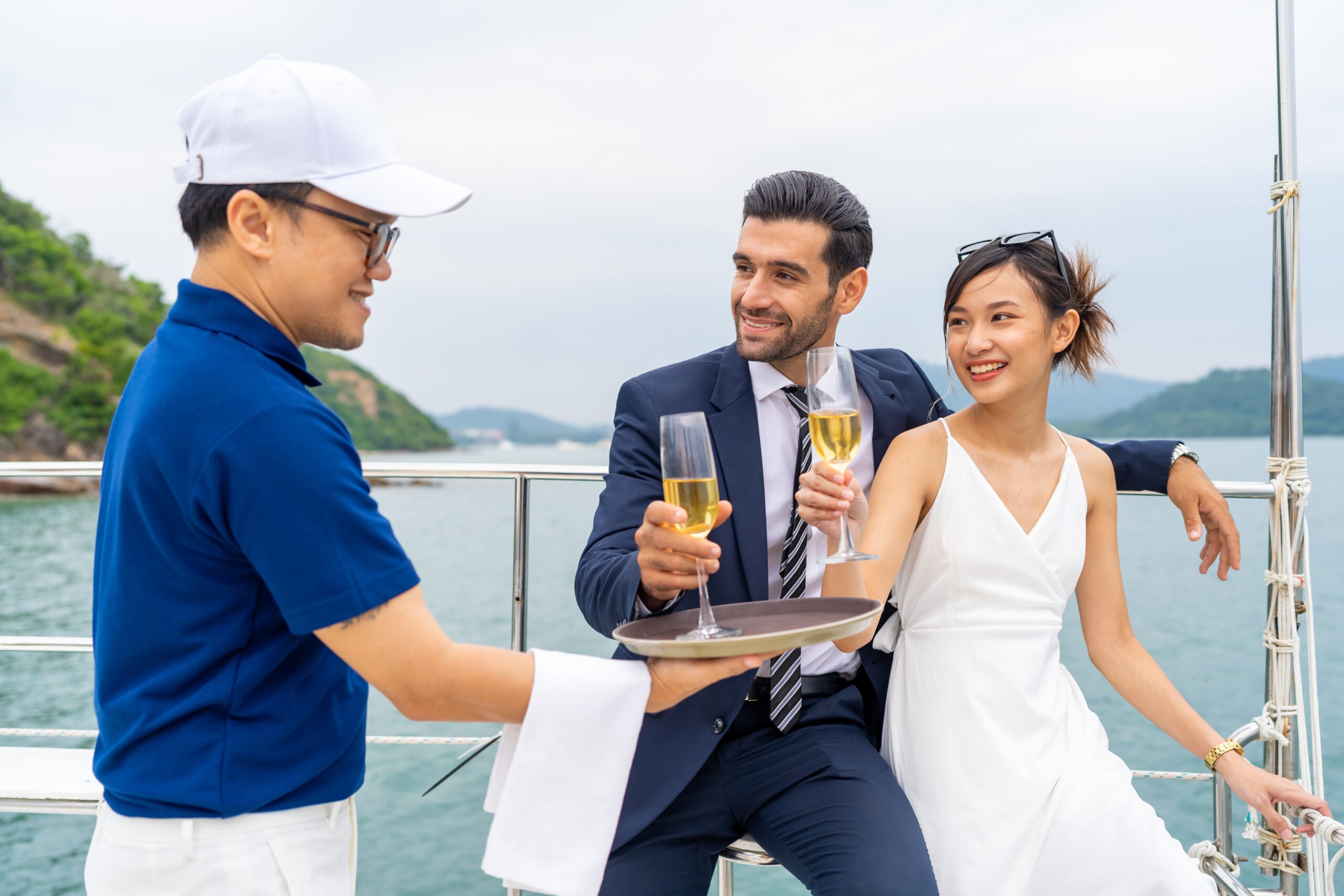 asian-man-waiter-serving-champagne-to-passenger-tourist-couple-on-luxury-yacht
