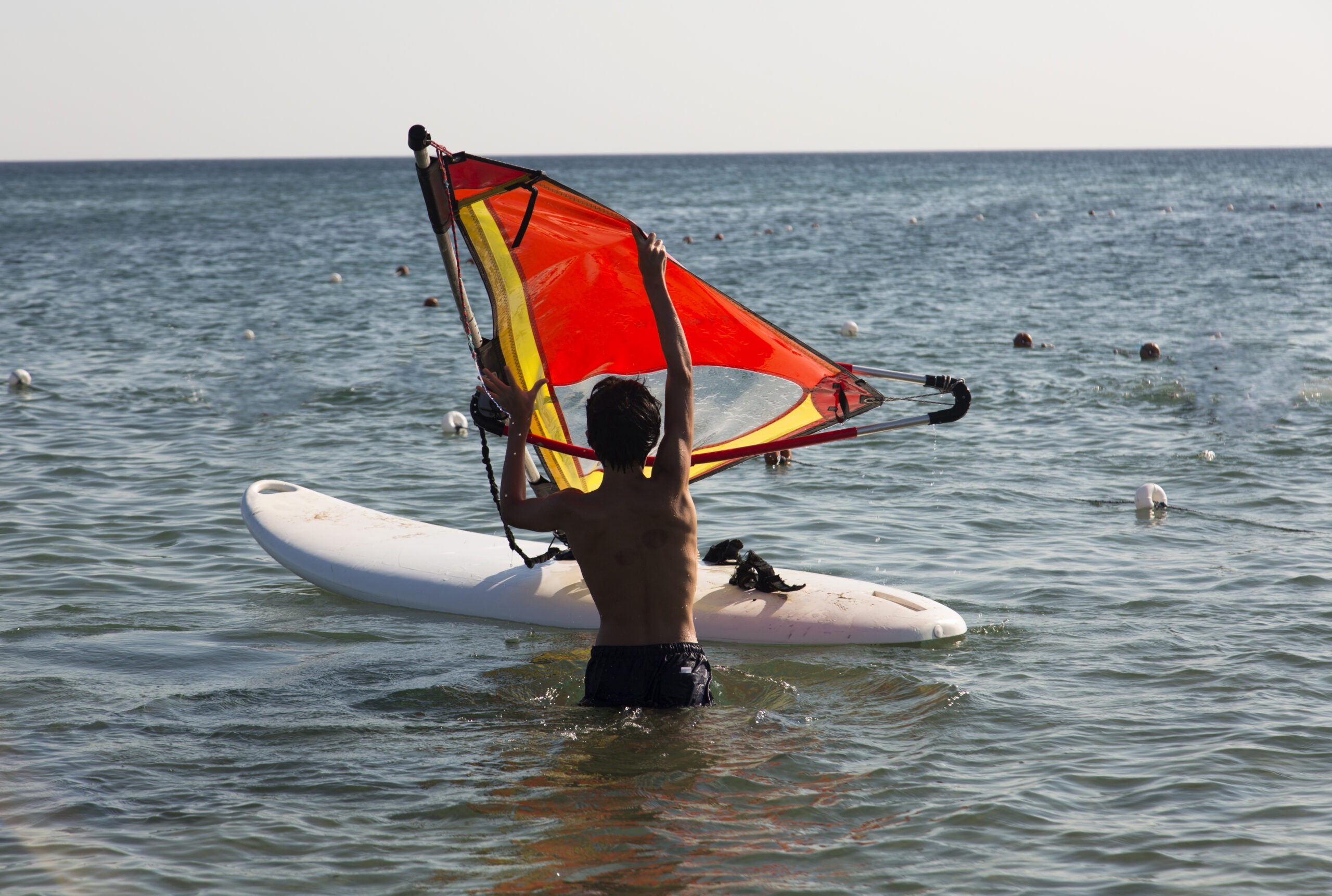 back-view-of-young-boy-surfer-in-the-sea-preparing-to-windsurf-on-a-sunny-summer-day