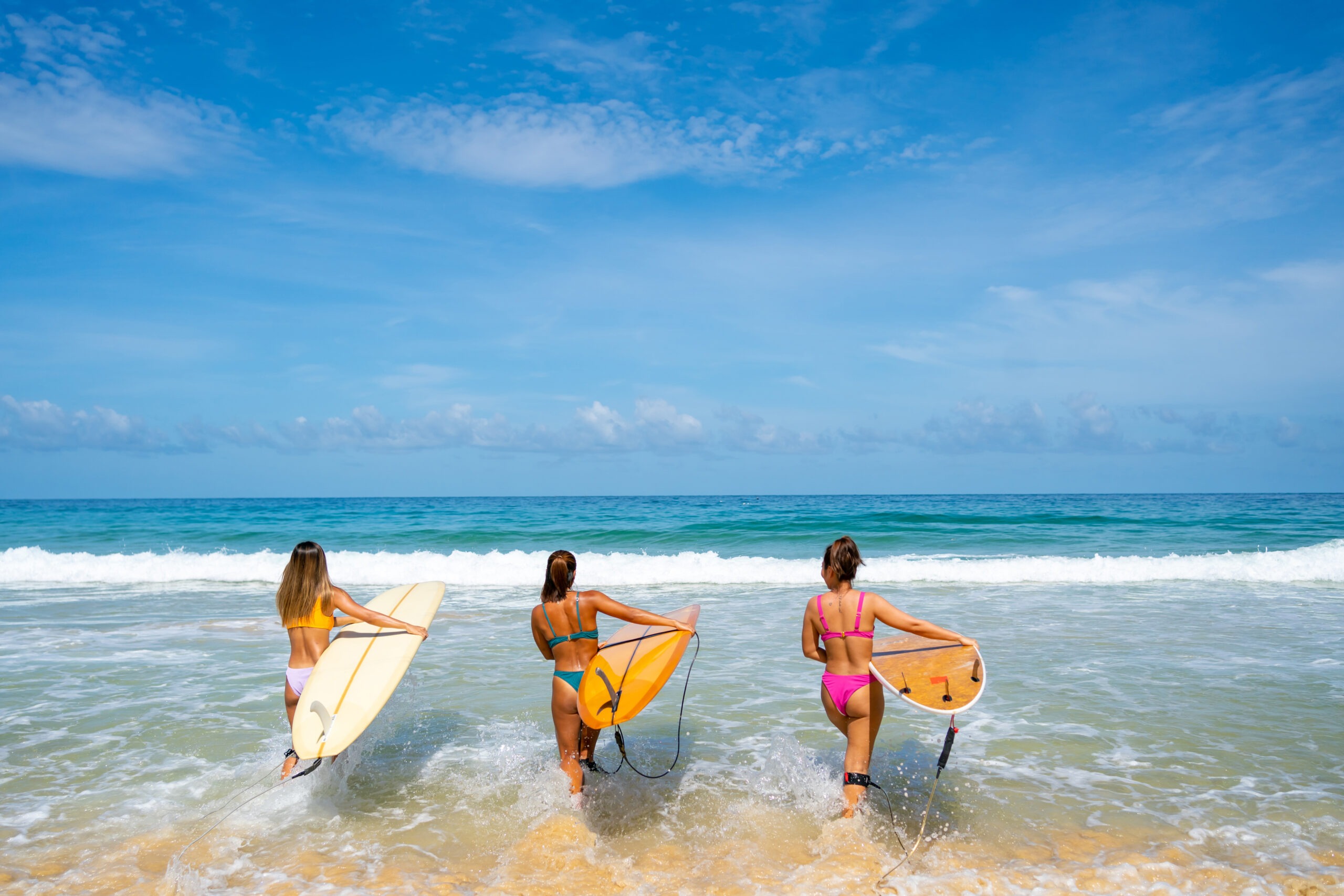 group-of-asian-woman-holding-surfboard-walking-together-on-the-beach-in-sunny-day