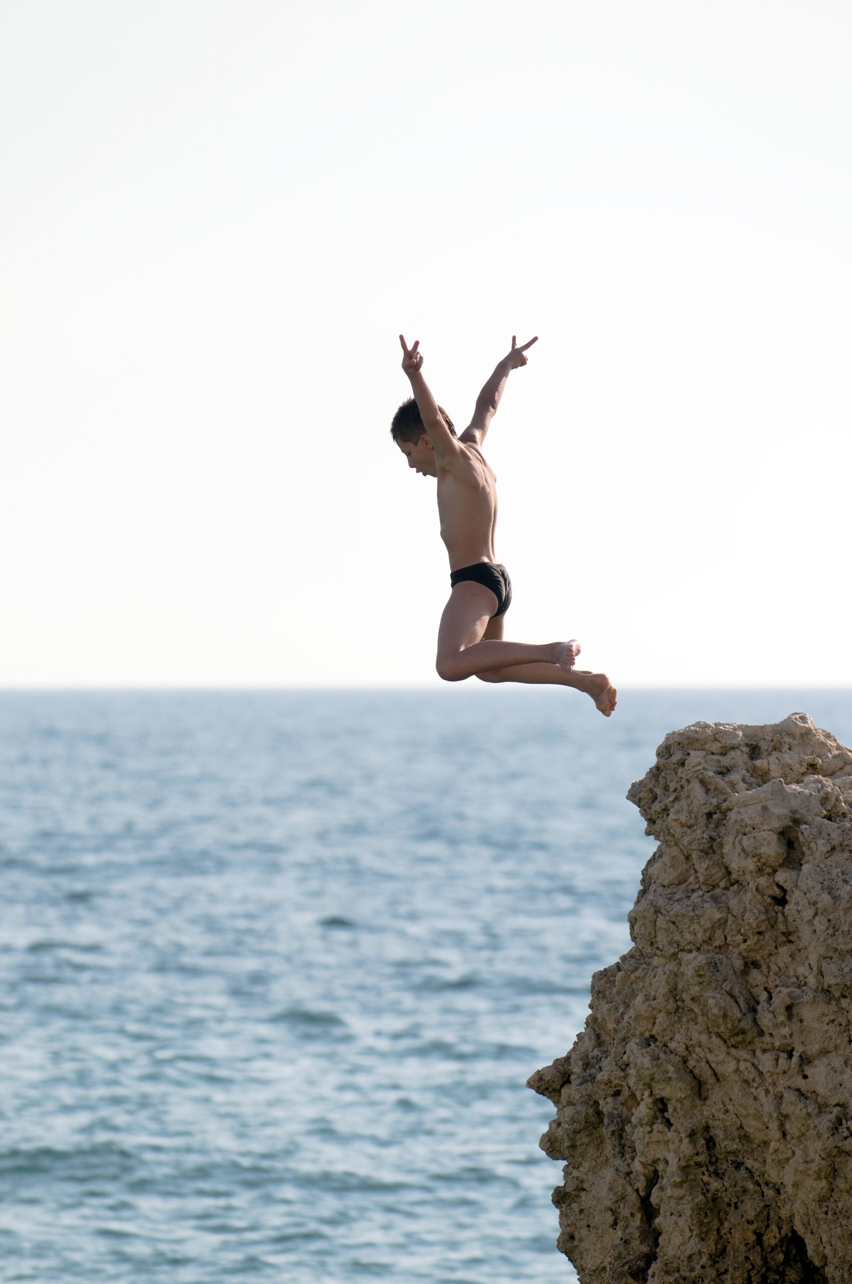 man-jumping-off-a-high-rock-into-the-sea
