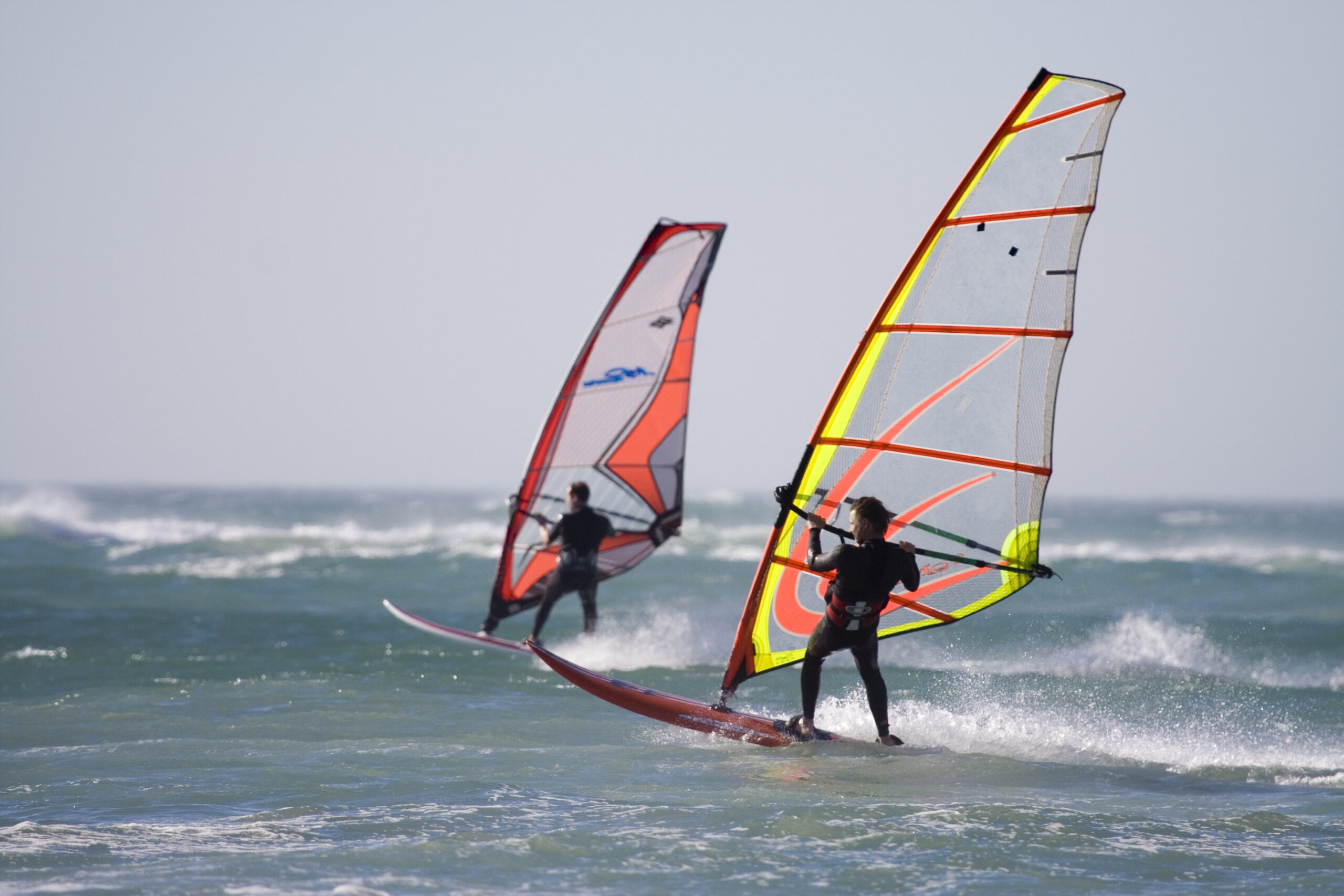 two-windsurfers-on-the-water-in-wetsuits