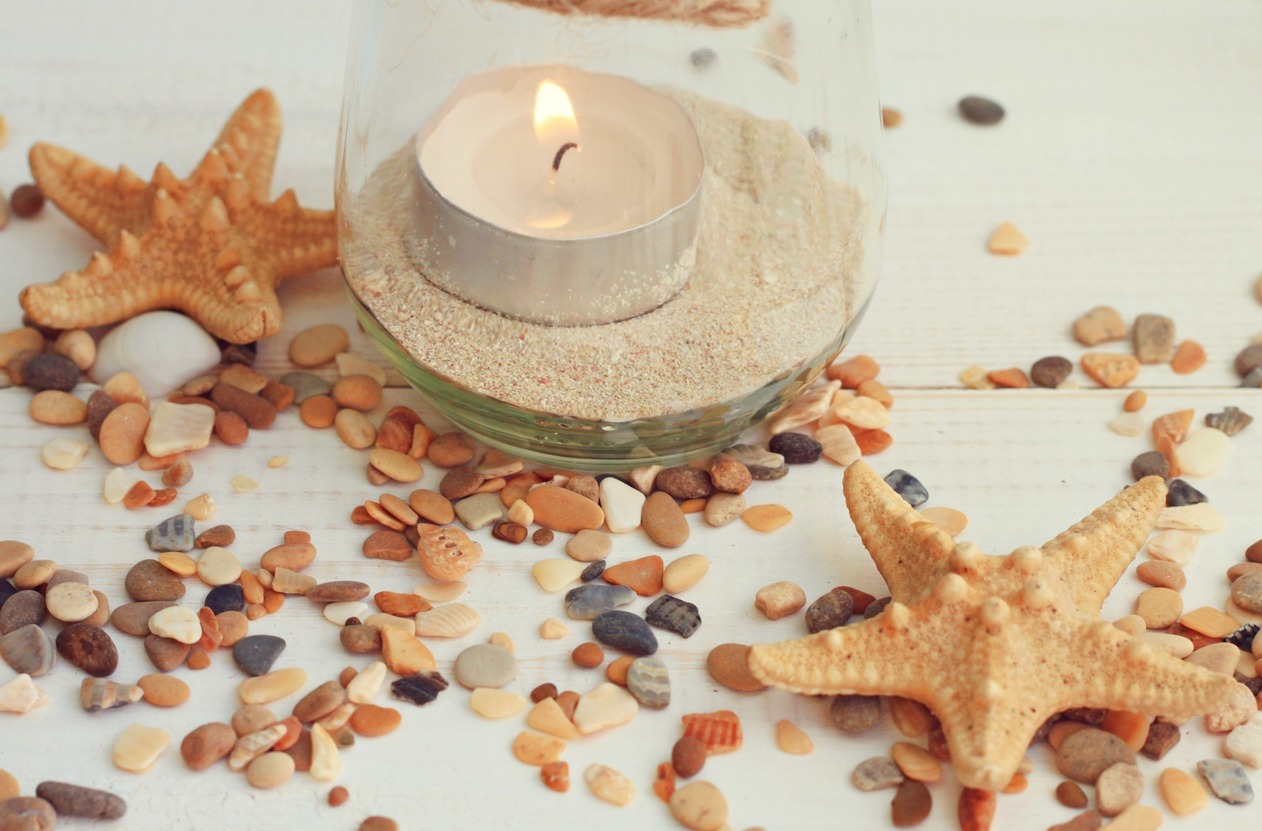 A-table-with-glass-filled-with-sand-and-tea-light-and-some-shells-and-starfish