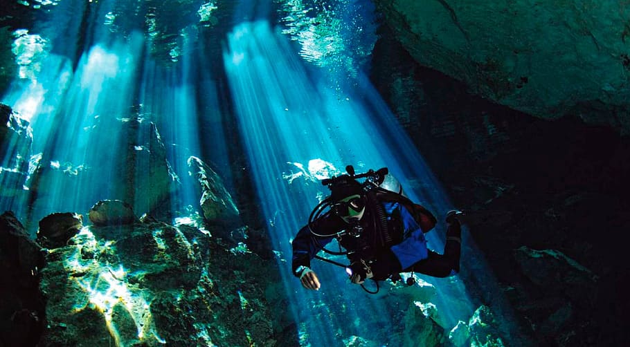 a-diver-on-an-underwater-cave-with-beams-of-sunlight