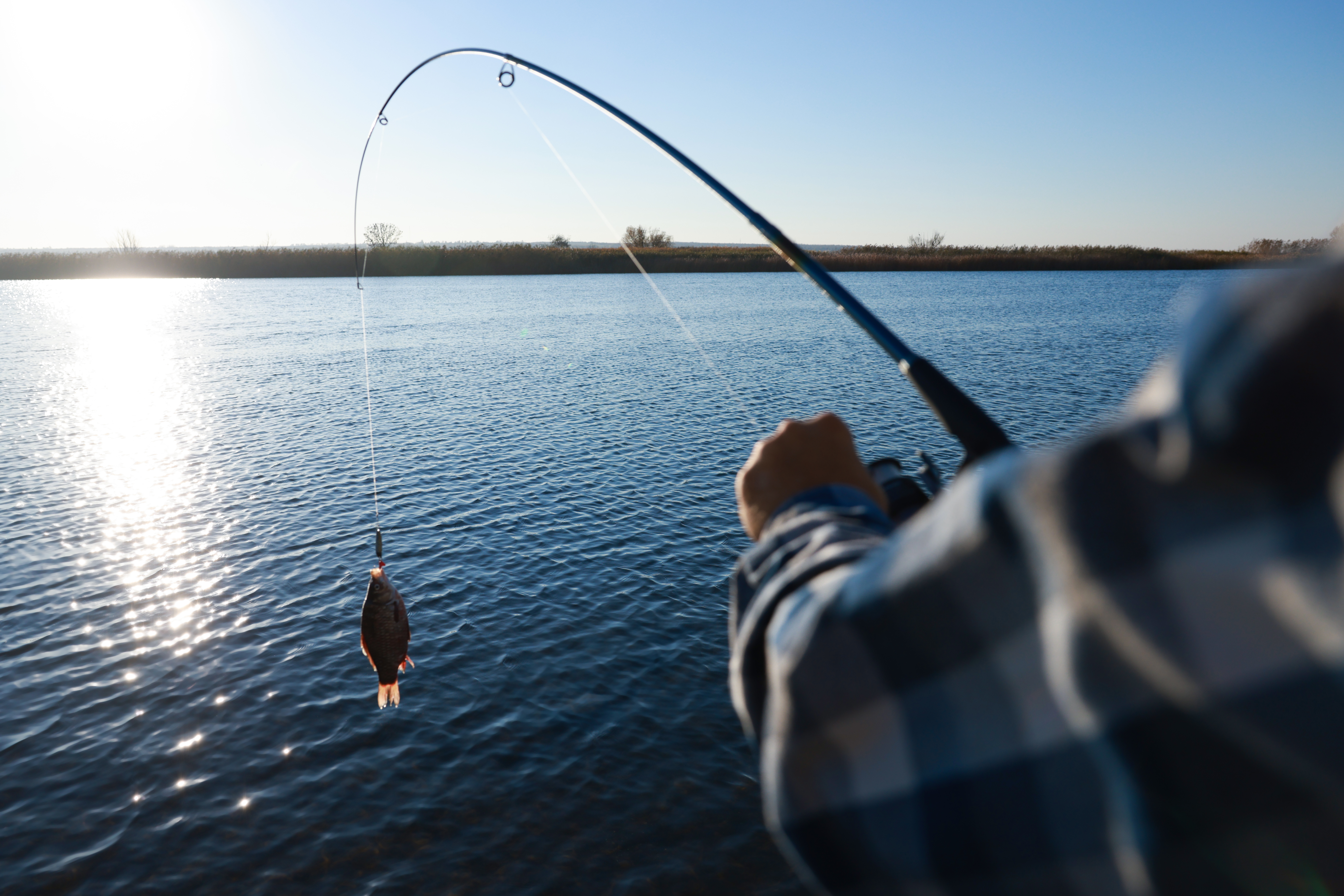 fisherman-catching-fish-with-rod-at-riverside-closeup