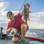 happy-fisherman-with-big-perch-fish-trophy-at-boat