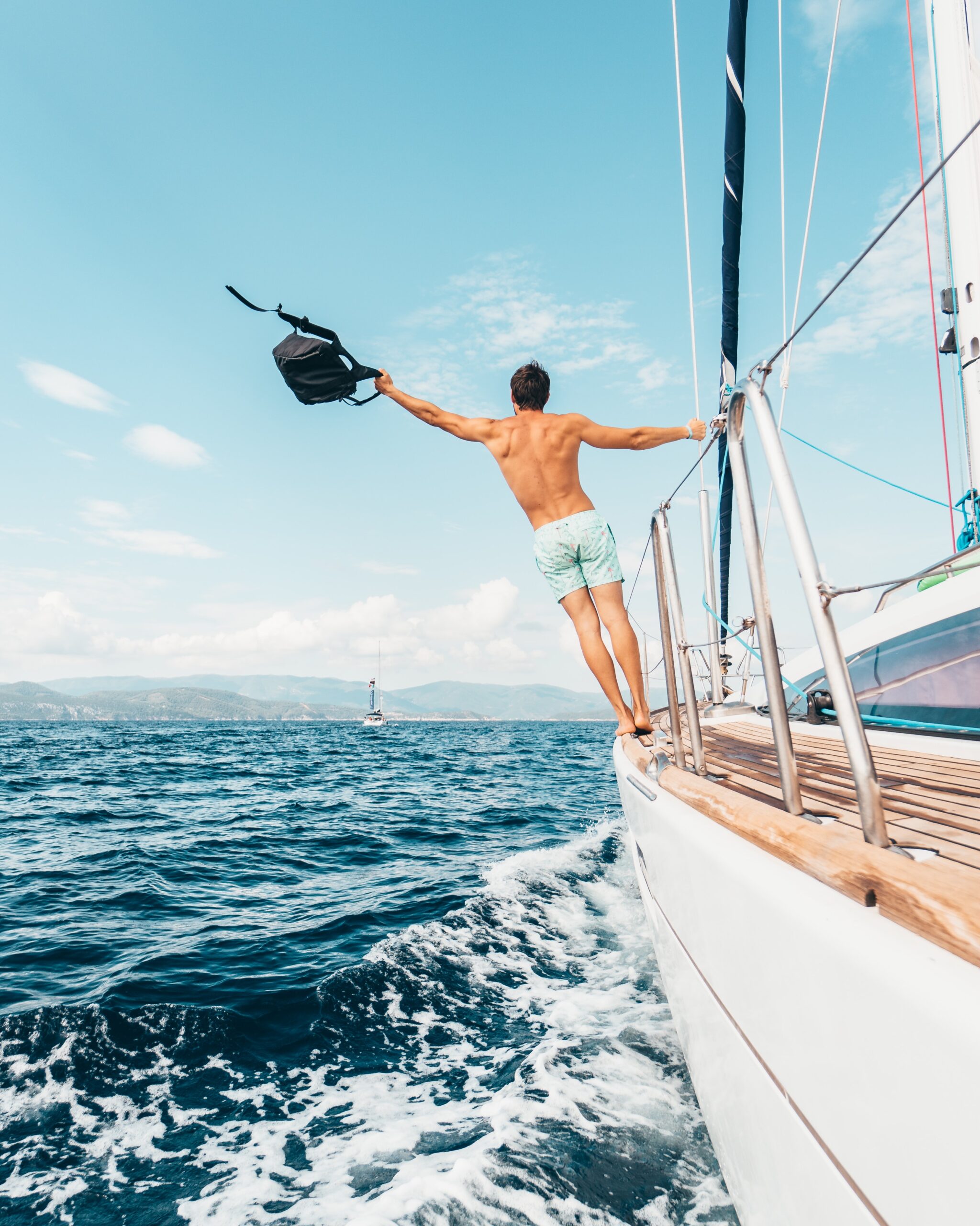 man-hanging-off-of-yacht