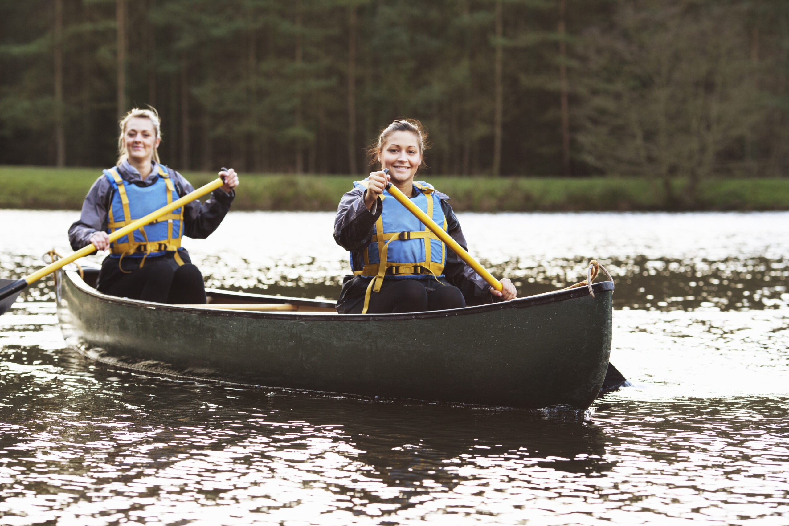 women-rowing-canoe-on-still-lake